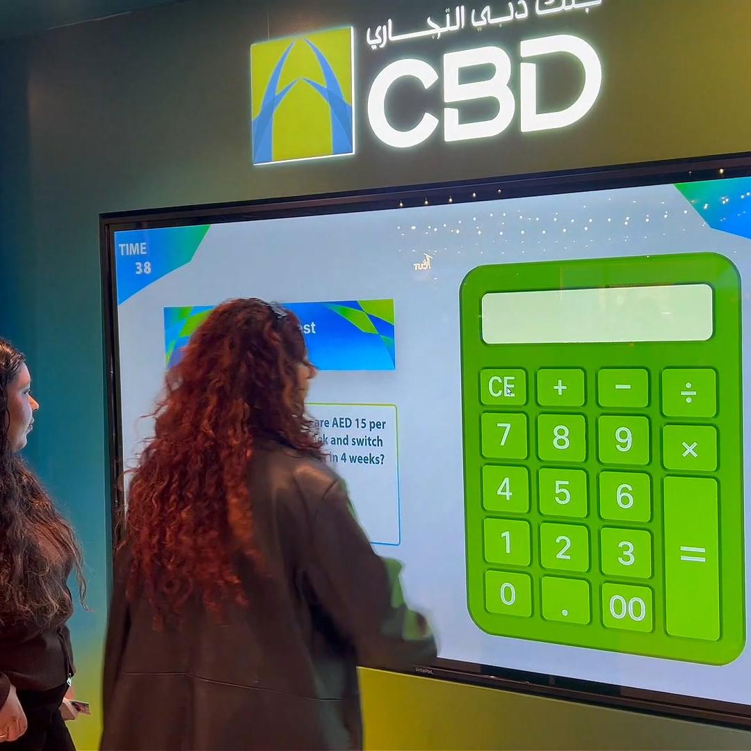 People playing a multi-level interactive financial literacy game at a brand activation event in Dubai, learning how to save and invest money.